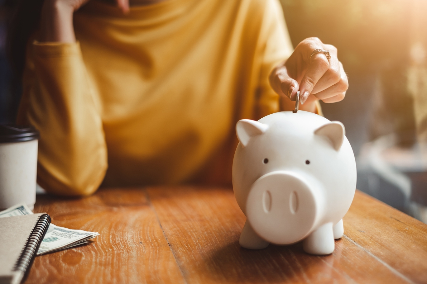 A woman putting change in a piggy bank.